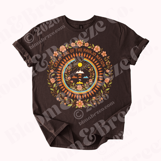 Brown “A Nation in Bloom” t-shirt featuring a floral Navajo Nation seal-inspired design in warm earth tones.