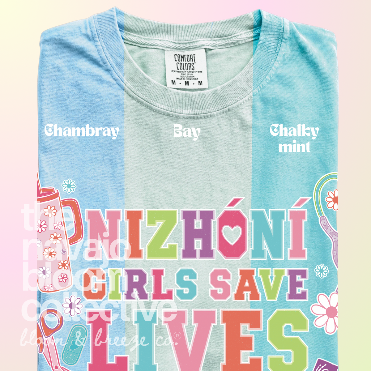 Nizhóní Girls Save Lives colorful lettering and medical-themed artwork on a Comfort Colors tee, comparing Chambray, Bay, and Chalky Mint.