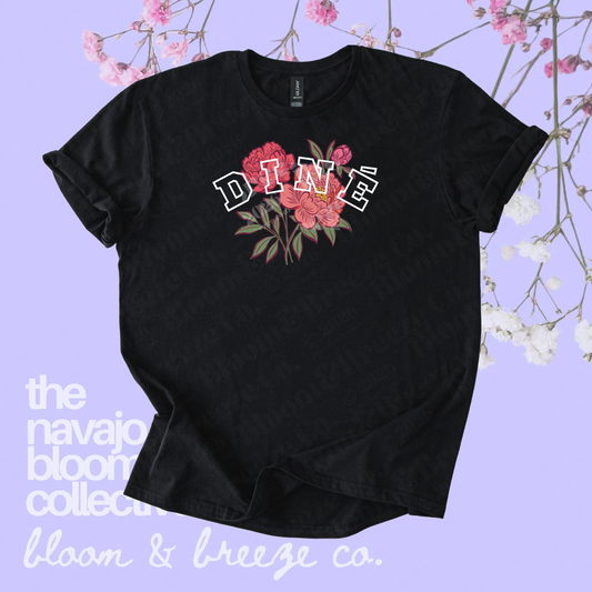 Black Diné floral graphic tee on a soft purple floral background.