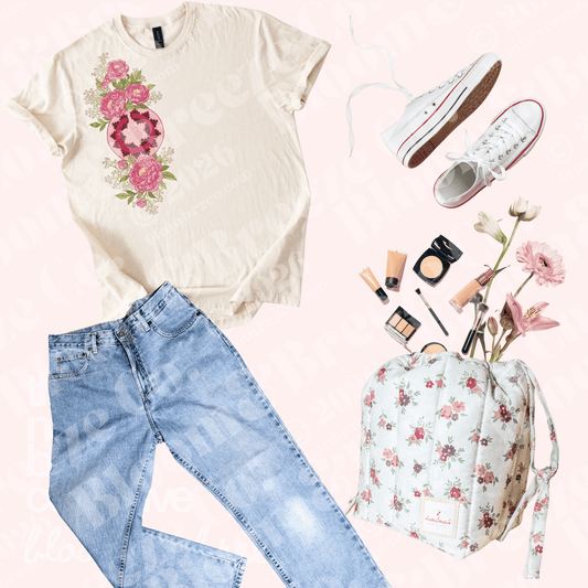 A styled flat-lay outfit featuring a cream graphic t-shirt with a pink floral design, light blue jeans, white low-top sneakers, a matching cream and pink floral backpack, and various makeup items, all arranged on a pale pink background.