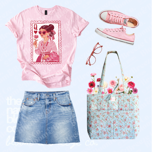 Pink Navajo Queen of Hearts-inspired graphic tee styled with a denim skirt, pink sneakers, pink glasses, and a light blue floral quilted tote bag.