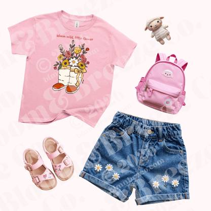Youth Rose Petal Pink ‘Bloom Wild, Little Flower’ graphic t-shirt styled with embroidered denim shorts, pink sandals, and matching backpack.