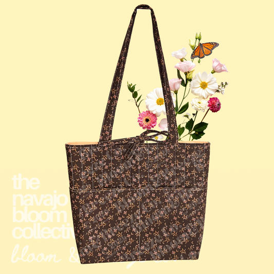 Brown floral quilted tote bag with long straps, front pockets, and flowers on a soft yellow background.