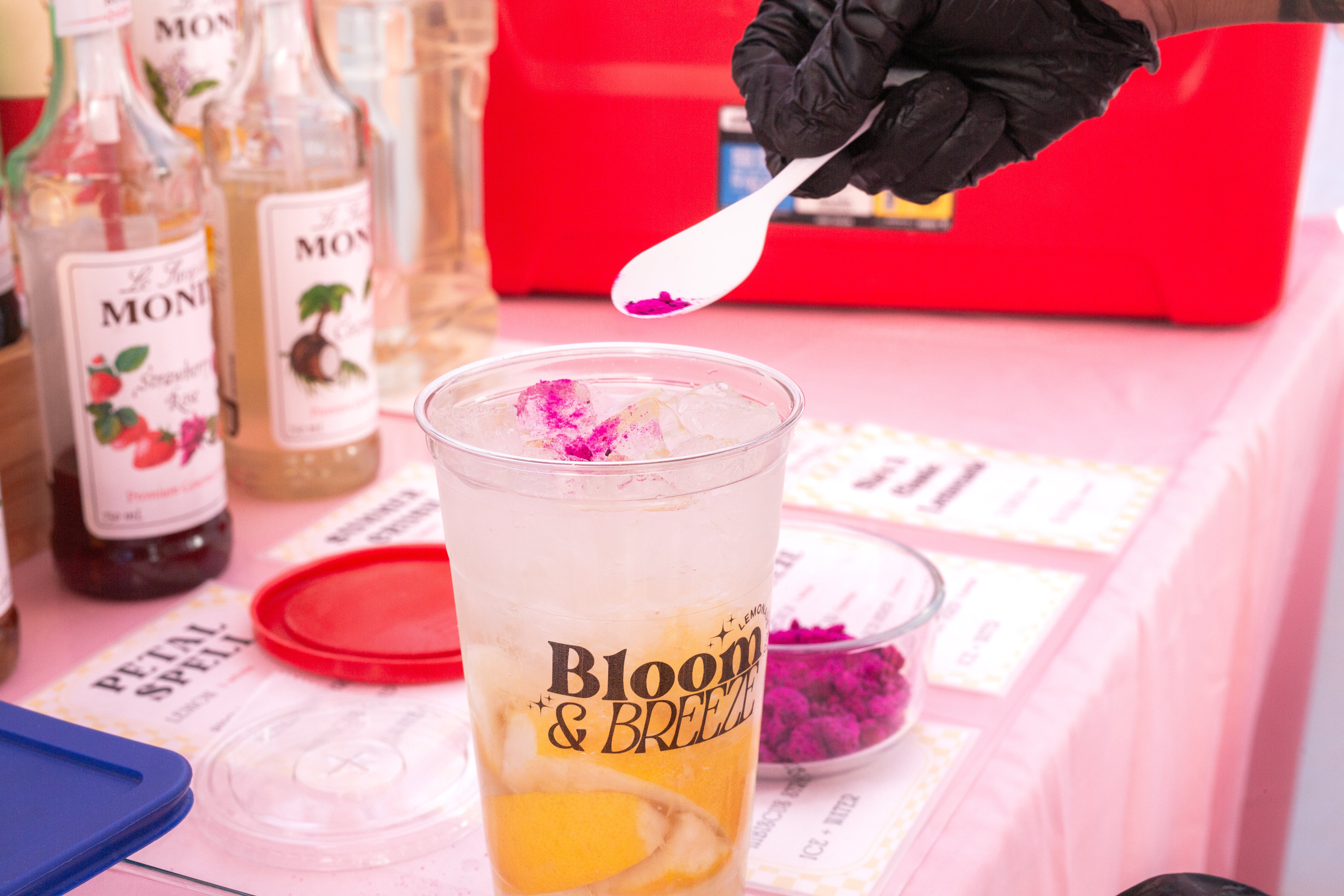 Close-up of a Bloom & Breeze co. drink with a spoon and bottles in the background.