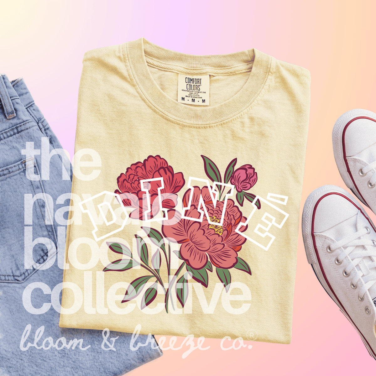 A folded cream-colored t-shirt with a pink floral graphic and the word 'dine' in white outlined letters. The shirt is styled in a flat-lay composition with blue jeans on the left and white sneakers on the right, set against a pastel pink and orange gradient background with 'the nameless bloom collective bloom & breeze co.