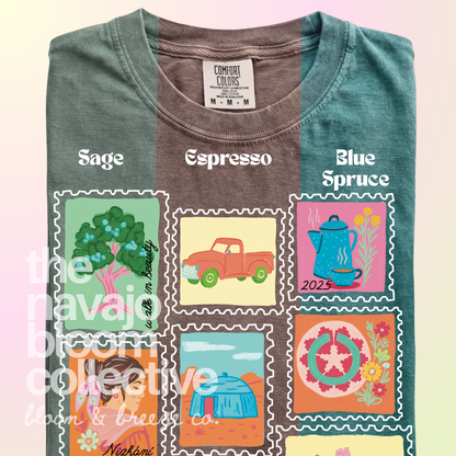 Dear Nizhóní stamp-style artwork on a folded Comfort Colors tee, comparing Sage, Espresso, and Blue Spruce.