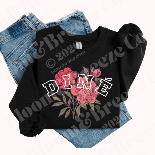 Black sweatshirt with floral design and 'DINé' text on a white background