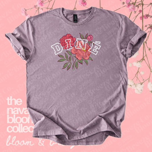 Lavender Diné floral graphic tee on a pink floral background.