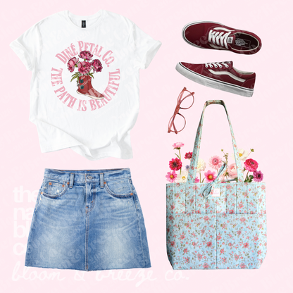 White Diné Petal Co. graphic tee styled with a denim skirt, red sneakers, pink glasses, and a light blue floral quilted tote bag.
