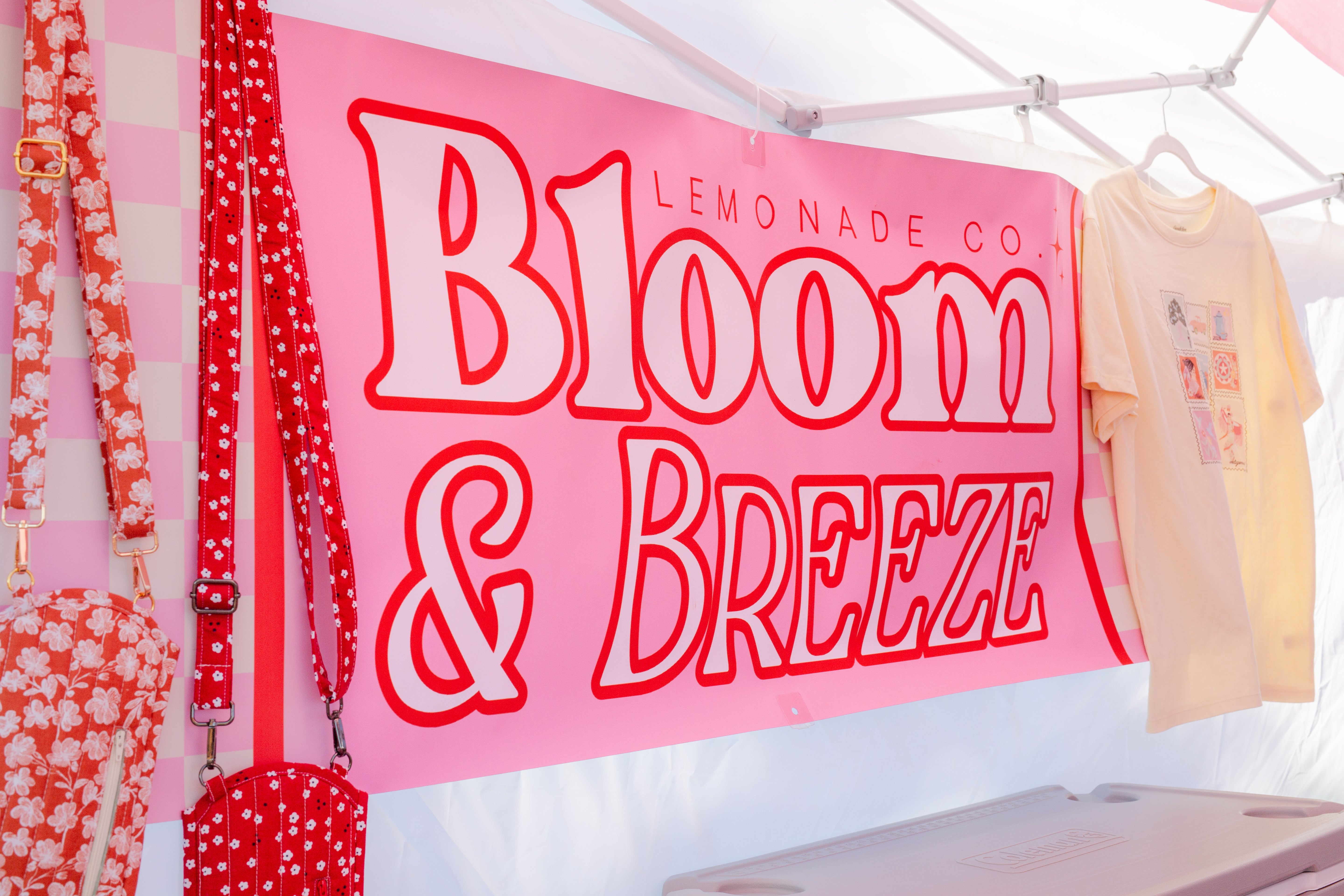 Pink banner with 'Bloom & Breeze' text at a lemonade stand.