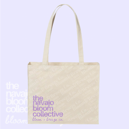 Beige tote bag with 'the navajo bloom collective' text on a light purple background