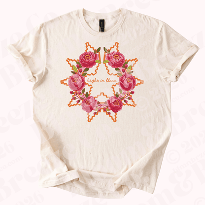 Beige t-shirt with Navajo wedding basket inspired design with peonies and text “Hozho in bloom” on a white background