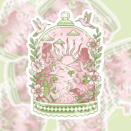Romantic desert birdcage sticker with pink Monument Valley sunrise, hummingbirds, and wildflowers.