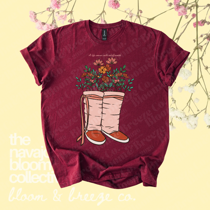 Maroon wildflower moccasin graphic tee with “A life woven with wildflowers” text on a soft yellow floral background.