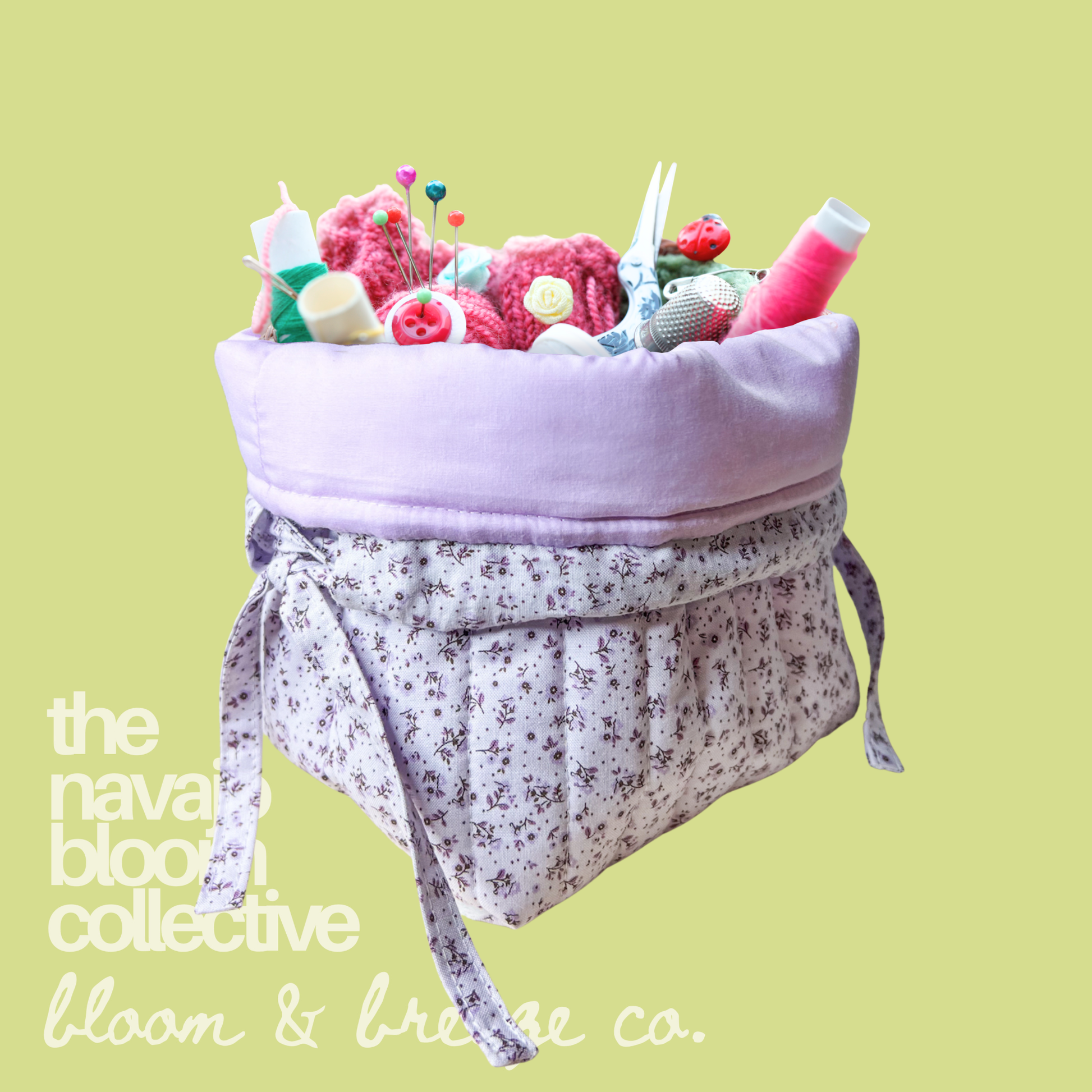 Lavender floral drawstring Petal Pouch filled with sewing notions, thread, pins, scissors, and yarn on a light green background with Bloom & Breeze Co. branding.