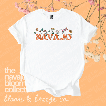 White Navajo floral graphic tee with orange lettering on a soft orange floral background.