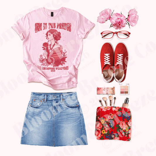 Pink “She Is the Prayer” graphic t-shirt styled with a denim skirt, red sneakers, red glasses, peonies, and a floral cosmetic bag.