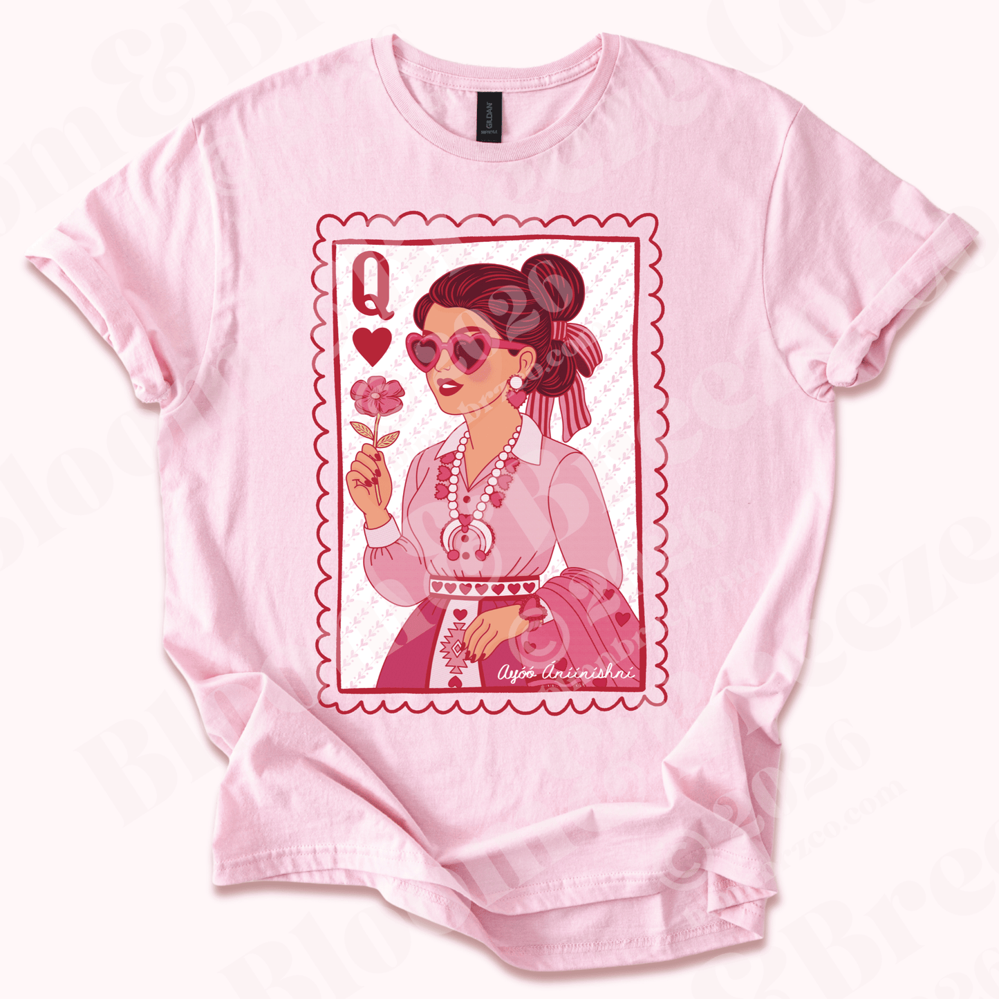 Pink t-shirt with a graphic design of a navajo cartoon woman holding a flower, wearing heart squash blossom, matching pink monochrome navajo traditional outfit on a white background