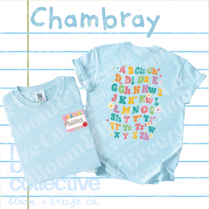 Two light blue t-shirts displayed on a lined paper background. The larger shirt shows a colorful alphabet print with flowers and the name 'Chambray' at the top.