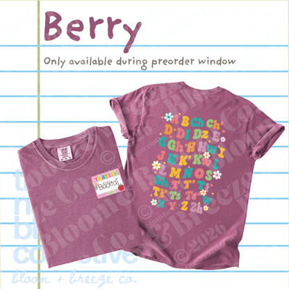 A folded and laid-flat berry purple t-shirt from Bloom + Breeze Co. on a lined paper background.