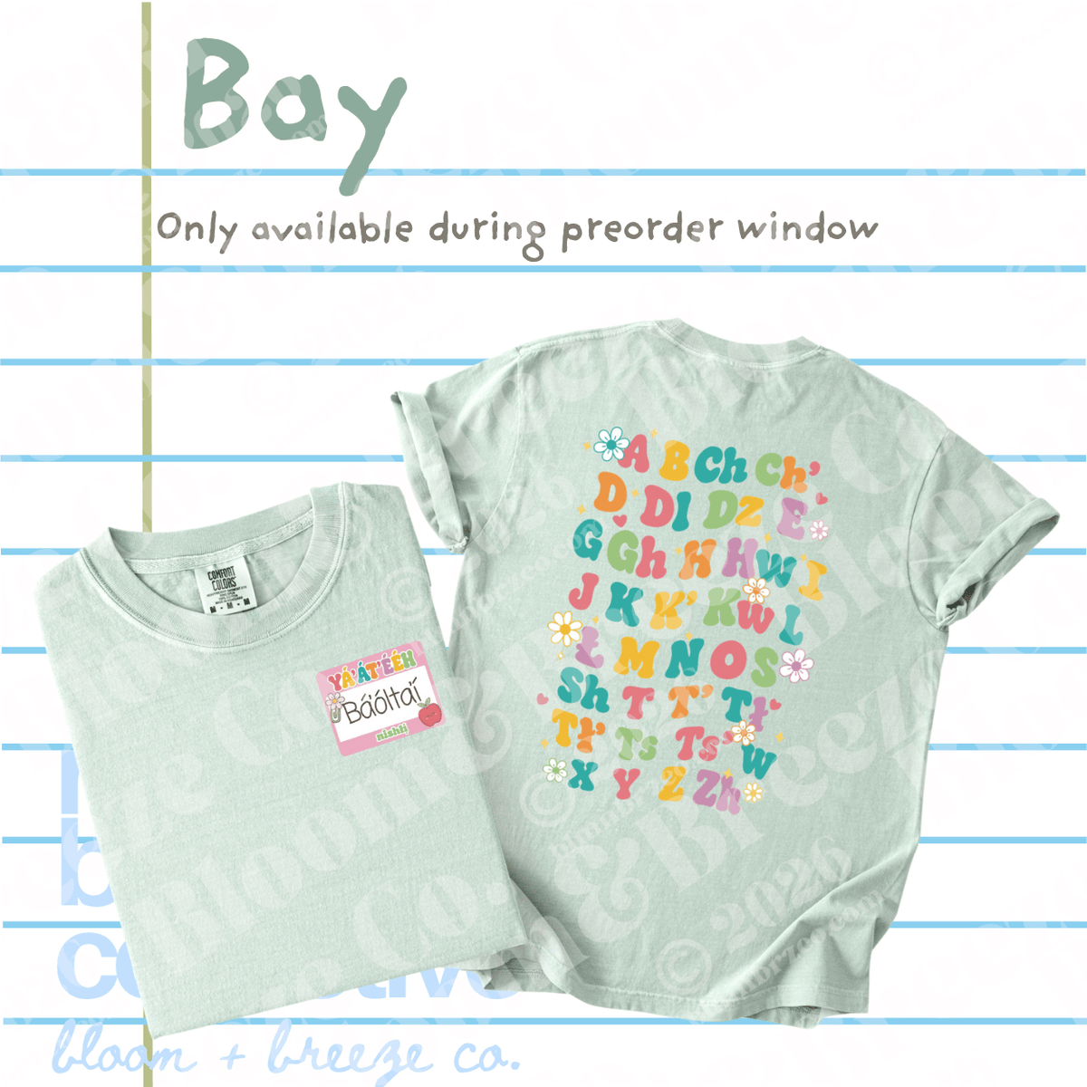 A light whitish green graphic t-shirt shown folded and flat, with text overlays reading 'Bay' and 'Only available during preorder window' on a lined paper background. The shirt features colorful alphabet letters with small floral accents on the back.