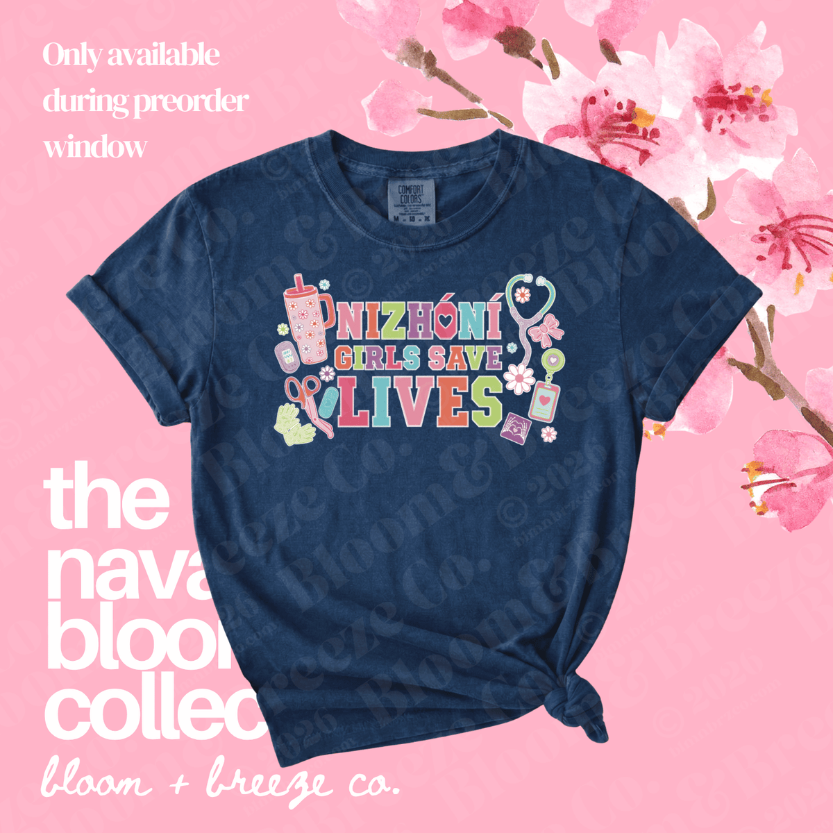 A navy blue graphic T-shirt with the phrase 'NIZhoni GIRLS SAVE LIVES' in colorful letters, surrounded by medical and care-themed illustrations. The shirt is styled on a pink background with floral graphics and text overlays reading 'Only available during preorder window' and 'the naval blood collection bloom + breeze co.