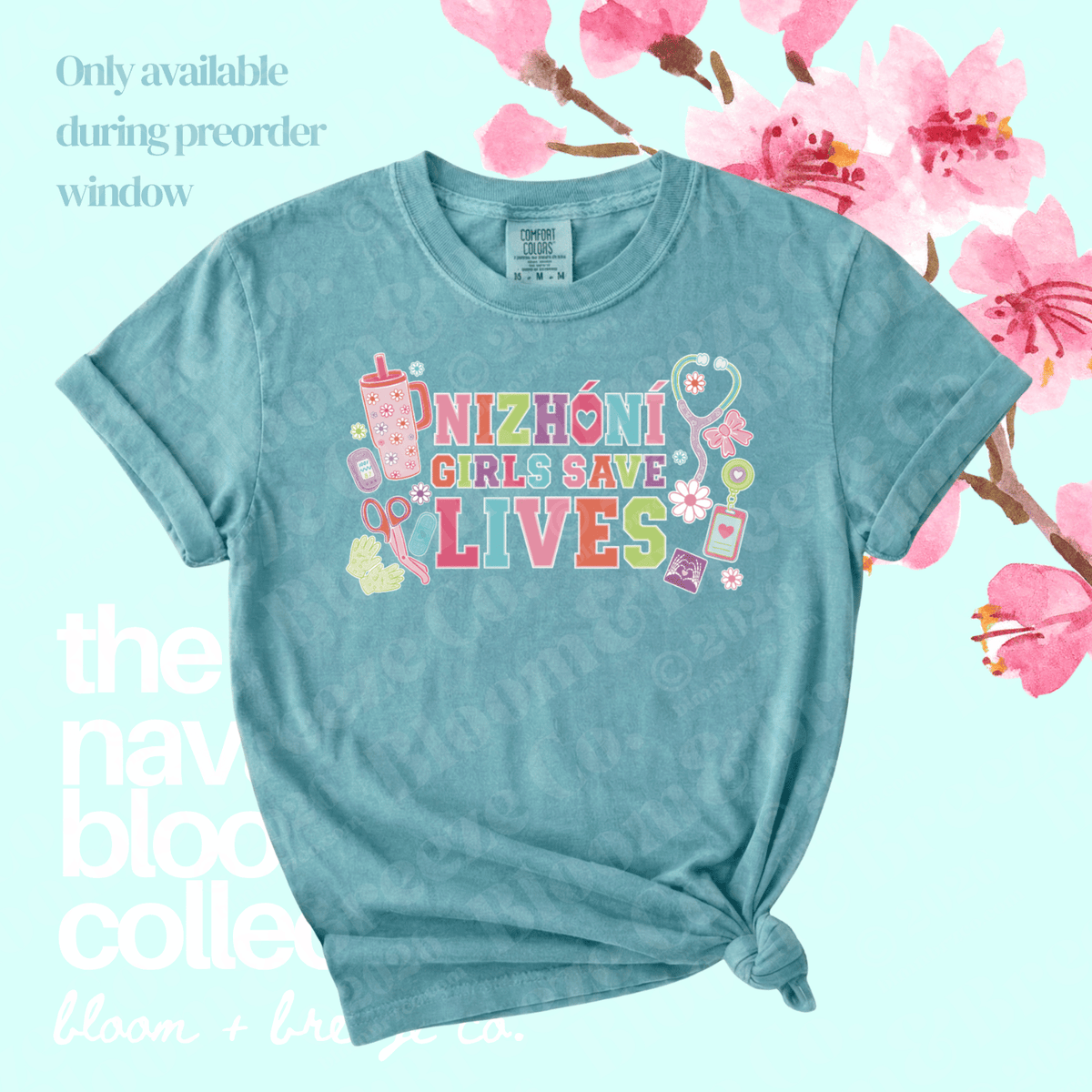 A light blue graphic t-shirt with 'NIZHONi GIRLS SAVE LIVES' printed in colorful retro letters, styled with a knot at the bottom hem. The shirt is displayed on a light blue background decorated with pink cherry blossoms and text overlays.