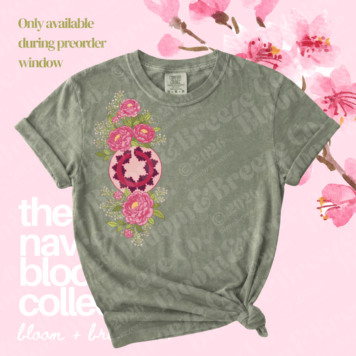 A short-sleeve crewneck t-shirt in a muted sage green, featuring a vertical graphic print of pink flowers and a central pink-and-white geometric heart design. The shirt is styled with a knot at the bottom hem against a light pink background decorated with cherry blossoms and text overlays.