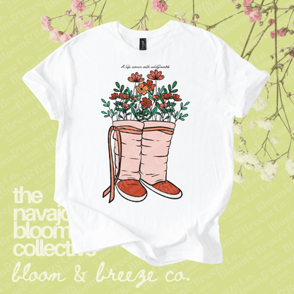 White t-shirt with floral boot design on a green background with floral elements.