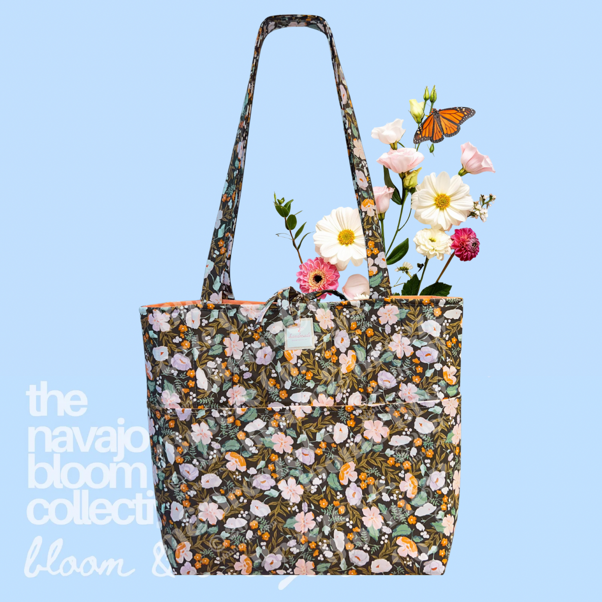Dark green floral quilted tote bag with long straps, front pockets, and flowers on a soft blue background.