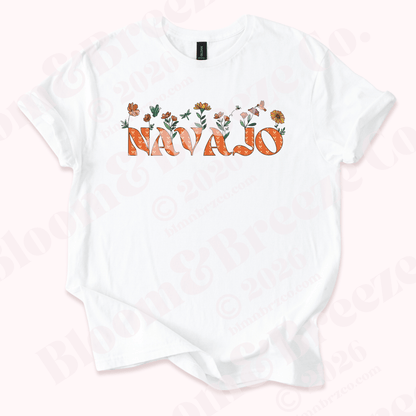 White t-shirt with 'Navajo' text and floral designs on a light pink background