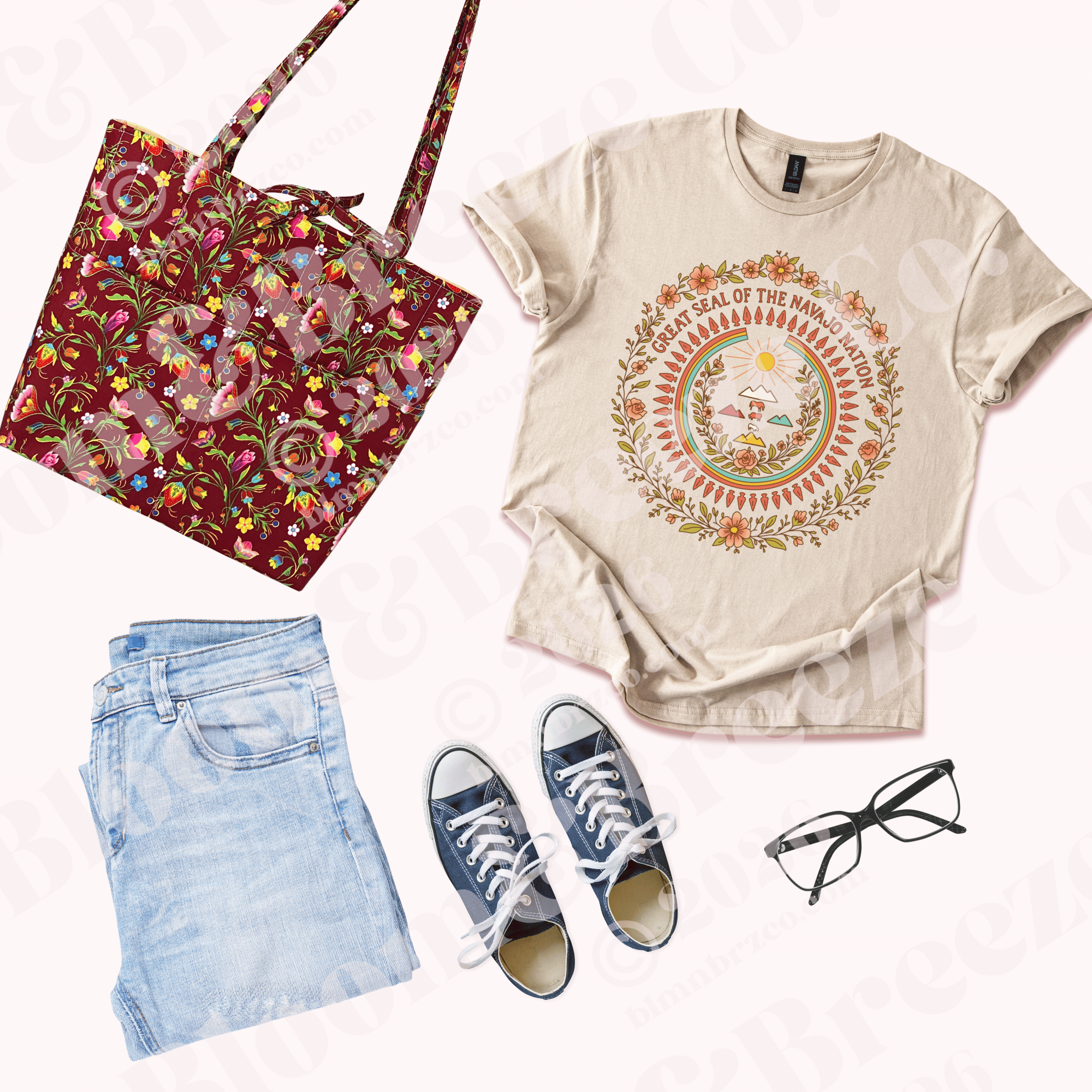 Flat lay outfit with a cream graphic T-shirt featuring a floral Great Seal of the Navajo Nation design, paired with light blue jeans, navy sneakers, black glasses, and a deep berry floral quilted tote bag.