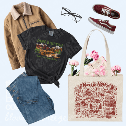 A styled flat-lay outfit featuring a black graphic t-shirt with a 'Diné Bikétah' print, a tan corduroy jacket, blue jeans, red sneakers, black glasses, and a beige canvas tote bag with 'Navajo Nation' artwork, arranged on a light blue background.