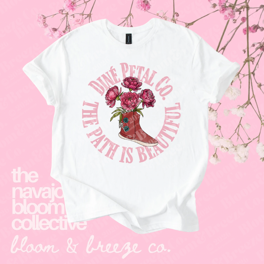 White Diné Petal Co. graphic tee with a floral boot design and “The Path Is Beautiful” text on a soft pink floral background.