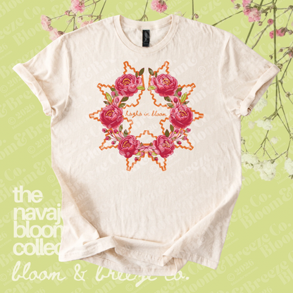 Cream Hózhó in Bloom floral graphic tee on a soft green floral background.