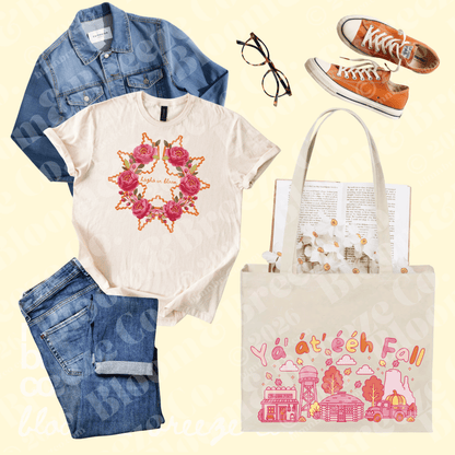 A flat-lay outfit arrangement on a pale yellow background featuring a cream graphic T-shirt with a pink rose wreath design, a blue denim jacket, blue jeans, orange sneakers, eyeglasses, and a cream tote bag with pink fall-themed illustrations and the text 'y'all at ech fall.'.