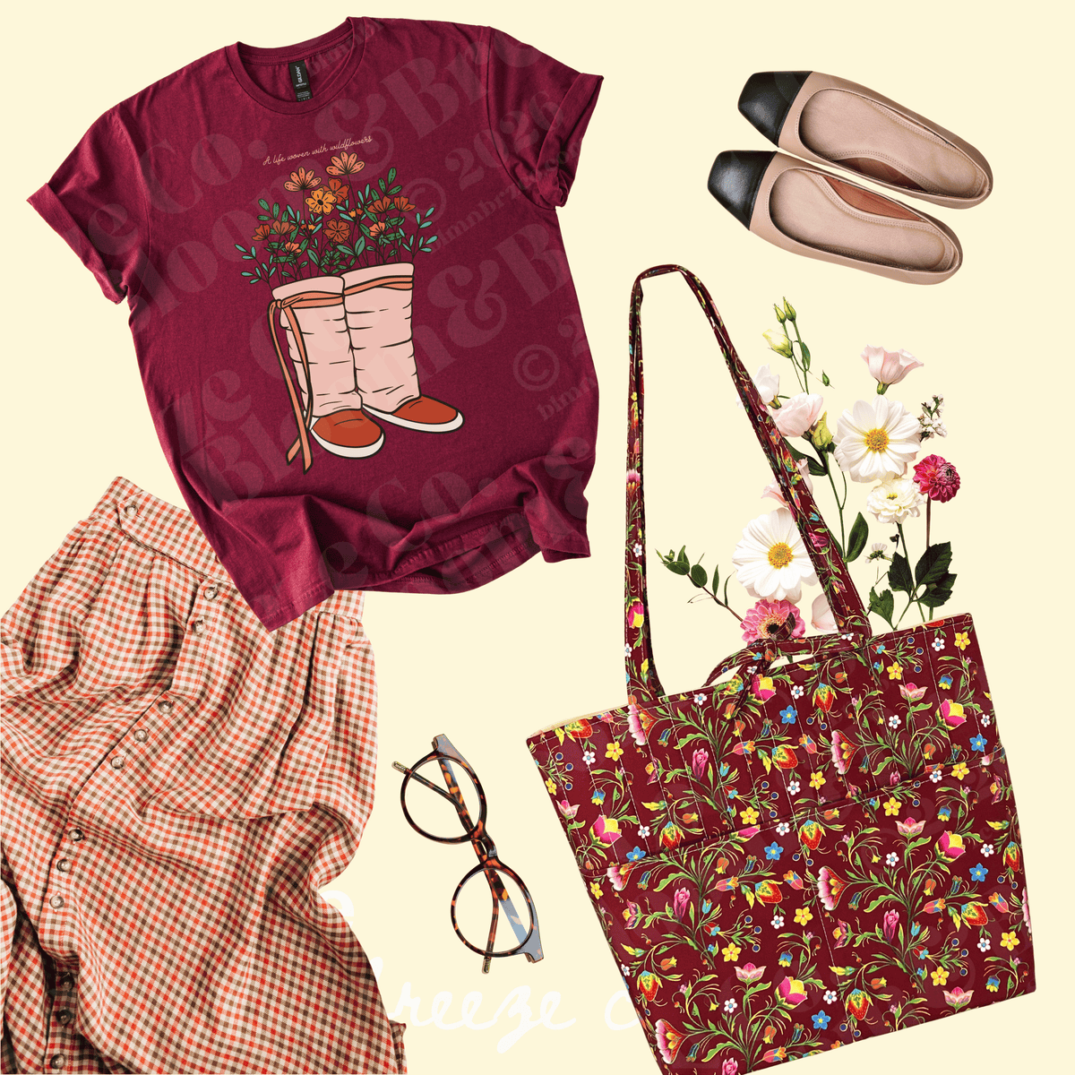 A flat-lay outfit arrangement featuring a burgundy graphic T-shirt with a floral boot print, a matching floral tote bag, a red-and-white gingham shirt, beige flats with black toes, and eyeglasses on a pale cream background.