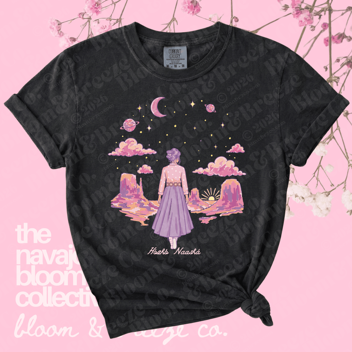 Black t-shirt with a colorful graphic of a woman in a purple dress standing on a planet, on a pink background with floral elements.